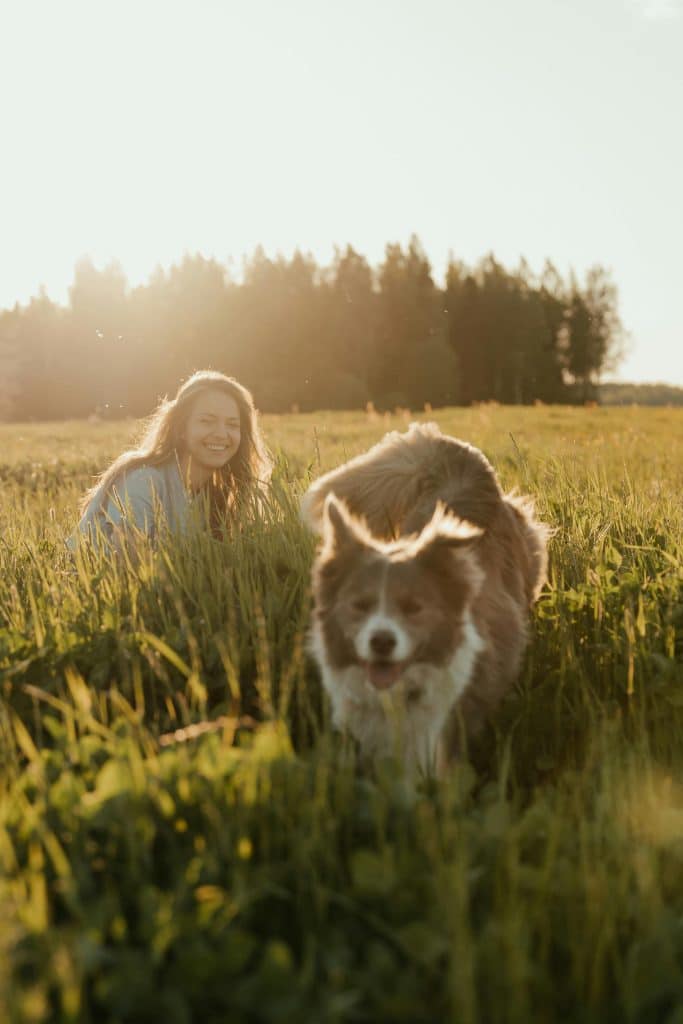 Woman in gray long sleeve shirt sitting on green grass field with brown and white long